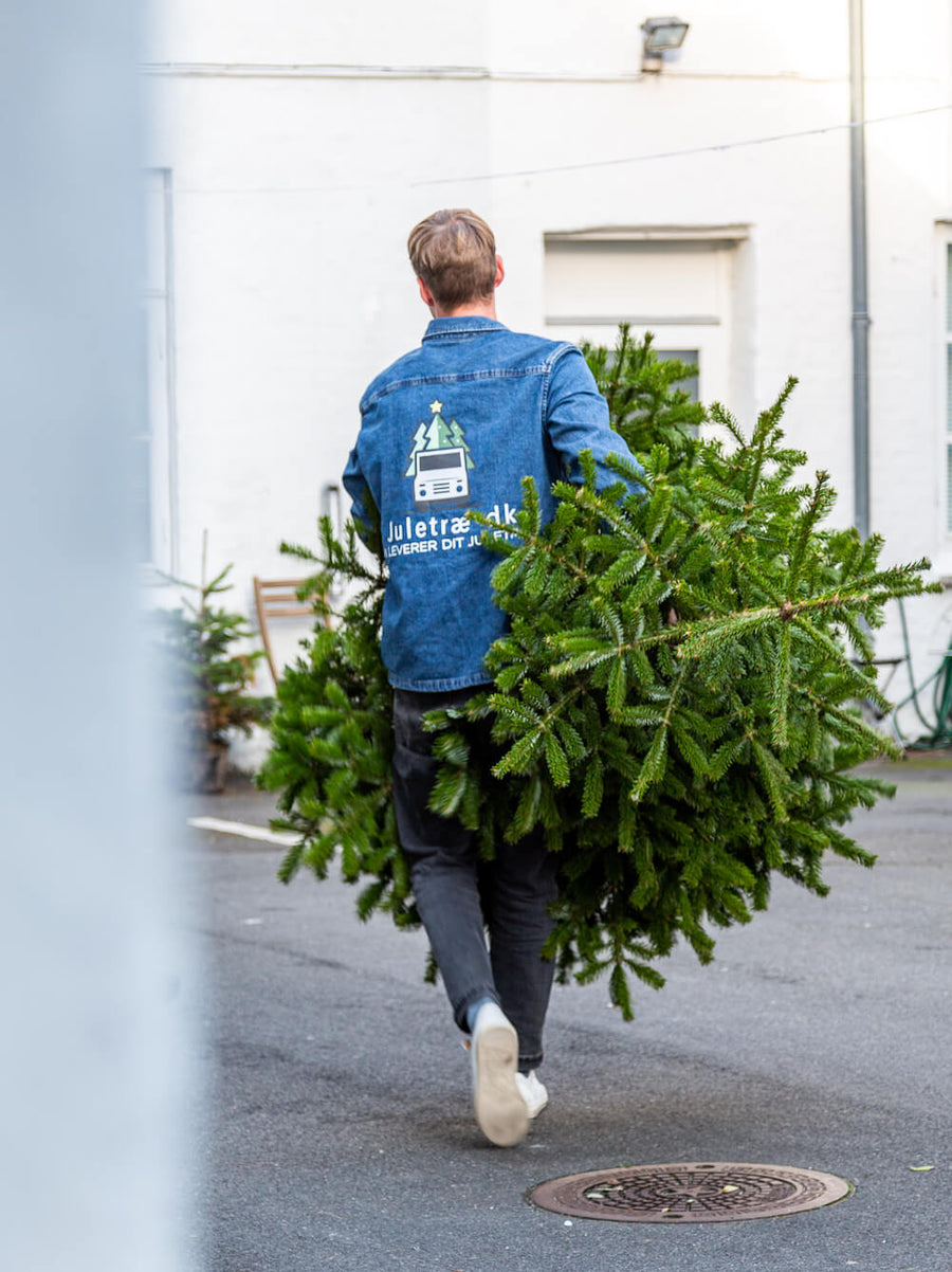 Medarbejder fra Juletræ.dk afhenter brugt juletræ ved døren