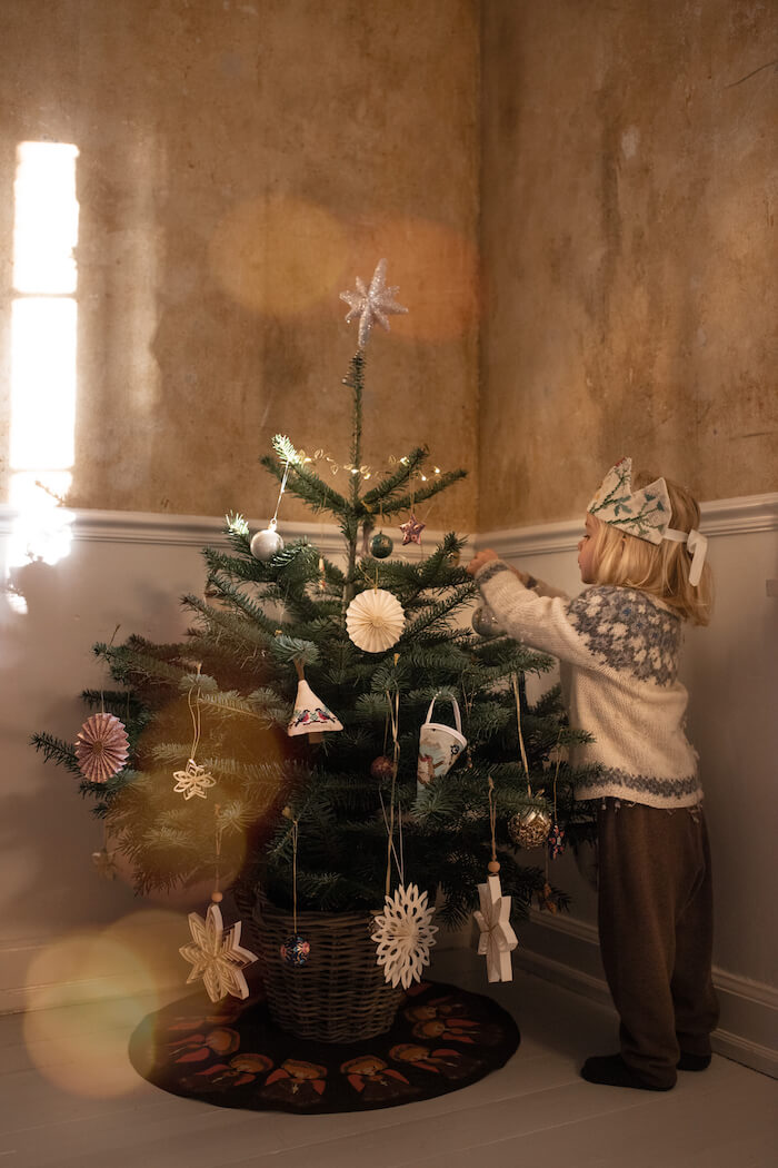 Juletræ i potte i flettet potteskjuler, pyntet i stuen